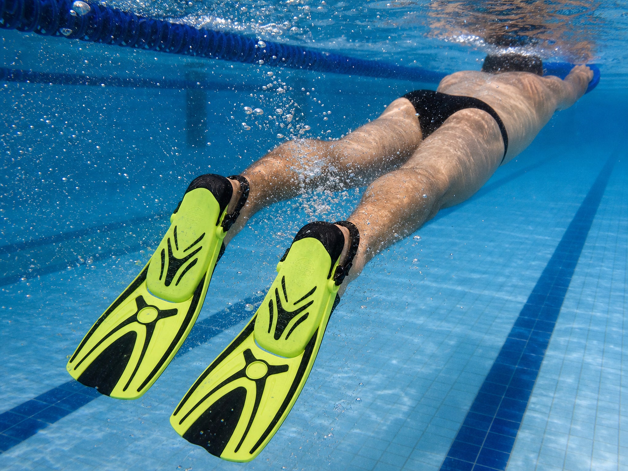 Swimmer training with a kickboard wearing yellow Tilos Aubade short blade fins