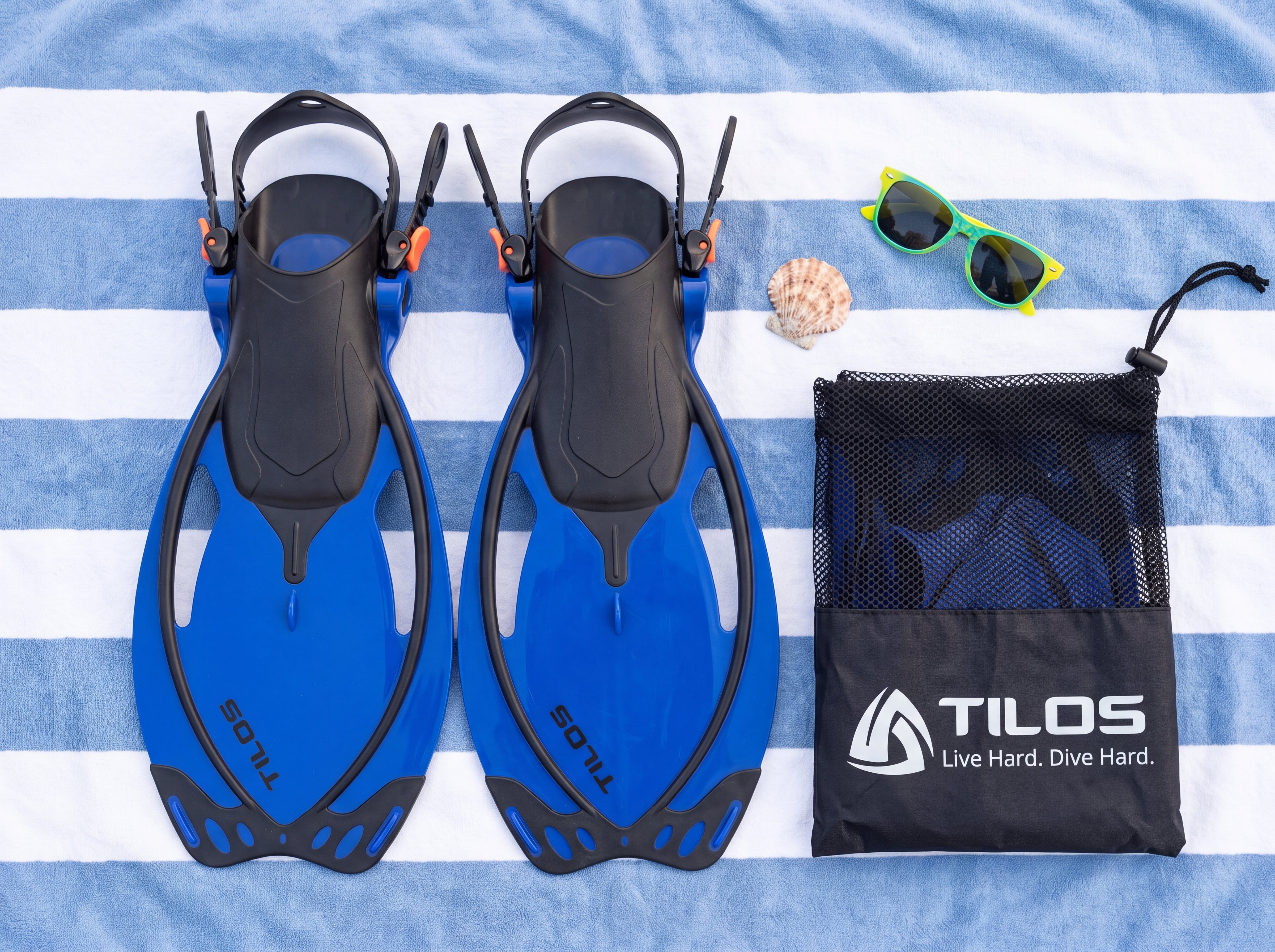 Tilos Vulcan Jr blue kids snorkel fins with mesh bag, beach lifestyle flatlay