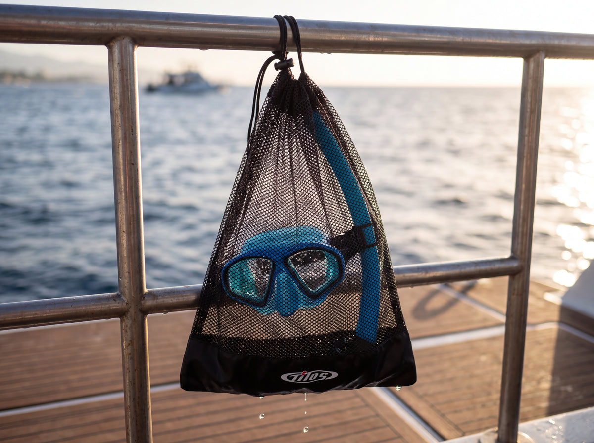 A diver has hung a black Tilos mesh mask and snorkel bag from a boat rail to drip dry after a dive.