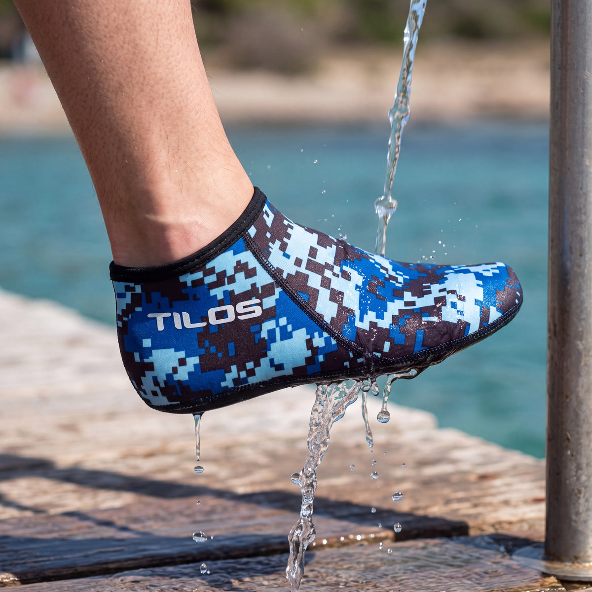 Diver rinsing sand off one foot under a jetty shower while wearing the Digital Blue camo Tilos 3mm Short Neoprene Sock