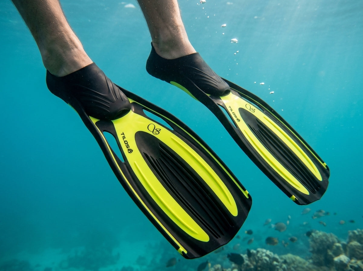 Snorkeler wearing Tilos Saber full foot fins in yellow underwater, close-up of the blades over a coral reef