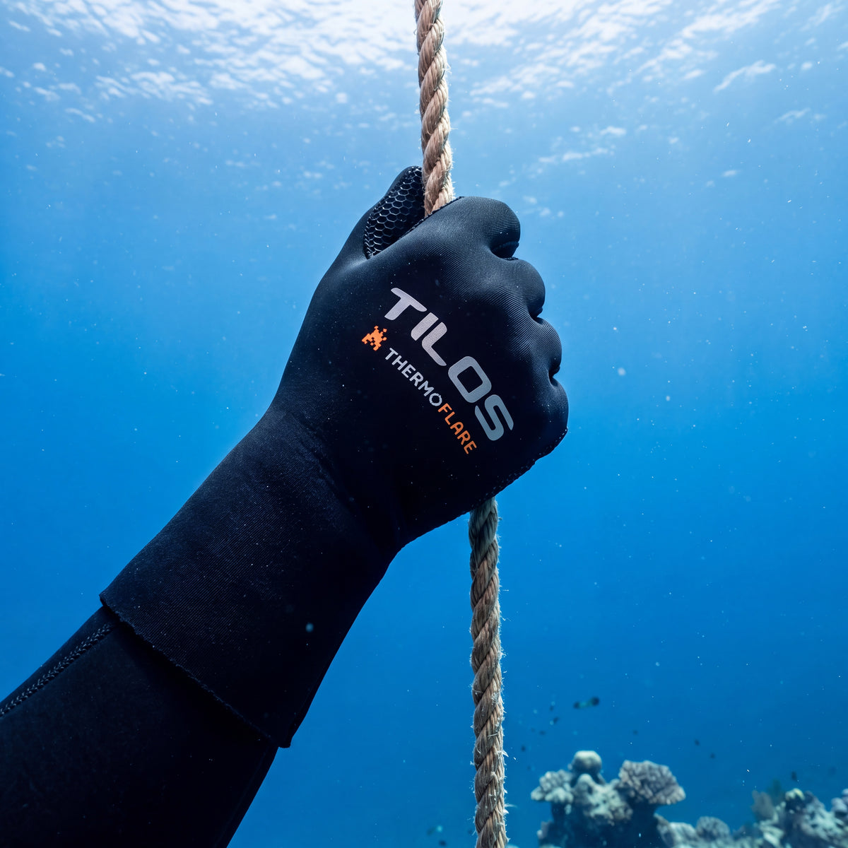 Diver gripping a shotline underwater during the descent, wearing black Tilos 3mm Thermoflare dive gloves.