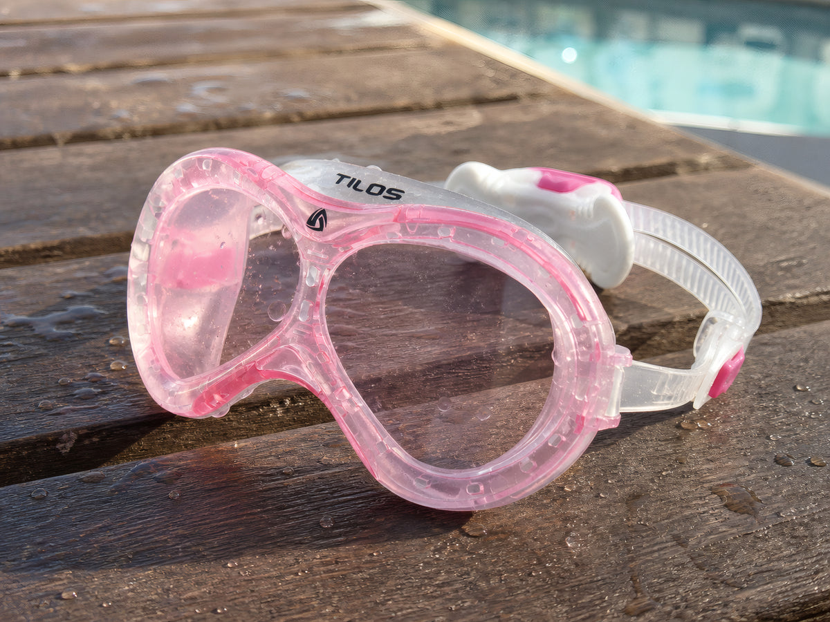 Pink Tilos Dyno toddler swim mask on a wet wooden bench poolside after a swim