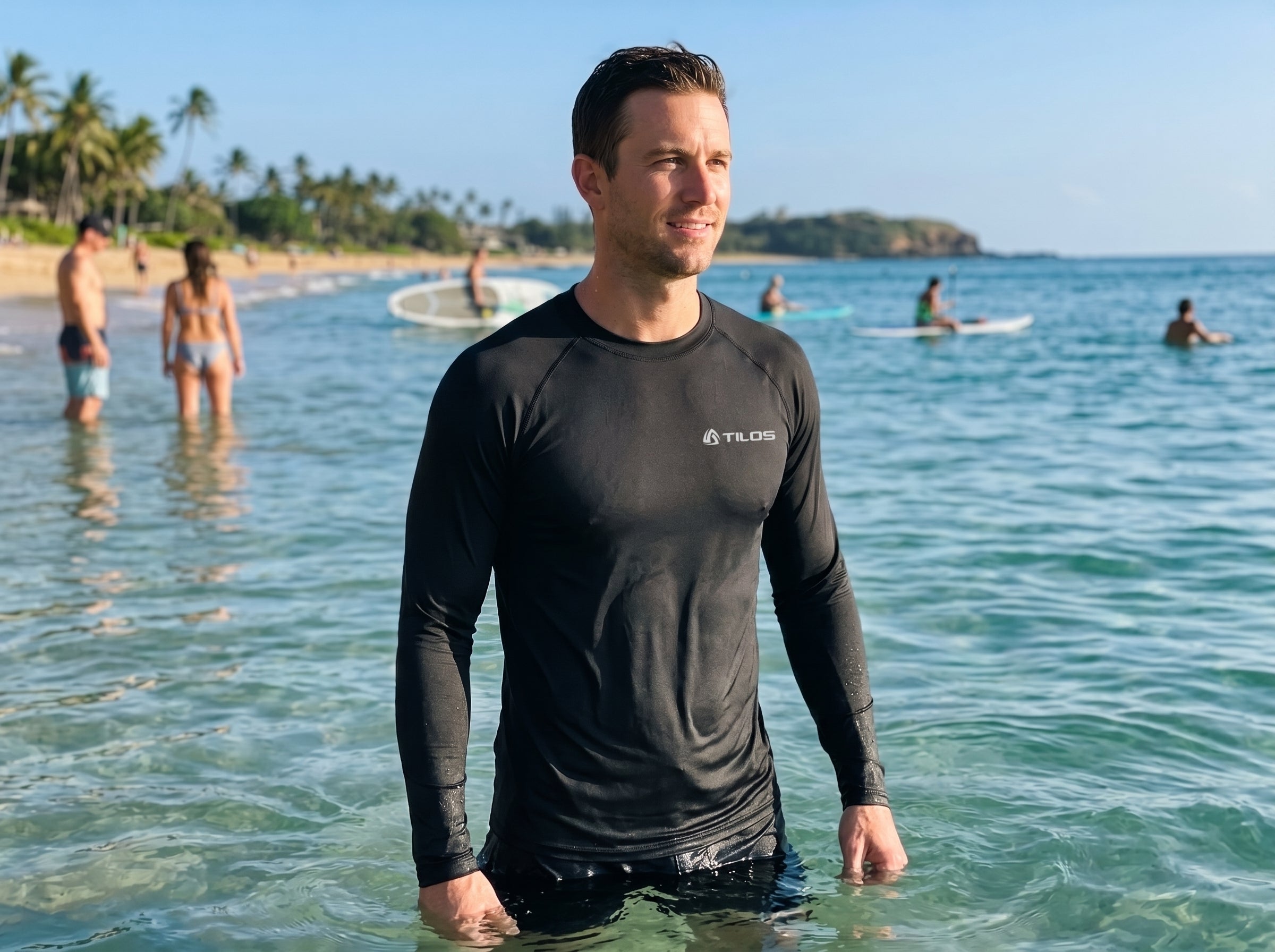 Man wading in shallow tropical surf wearing the Tilos Men's 6oz Anti-UV Long Sleeve Rash Guard in black