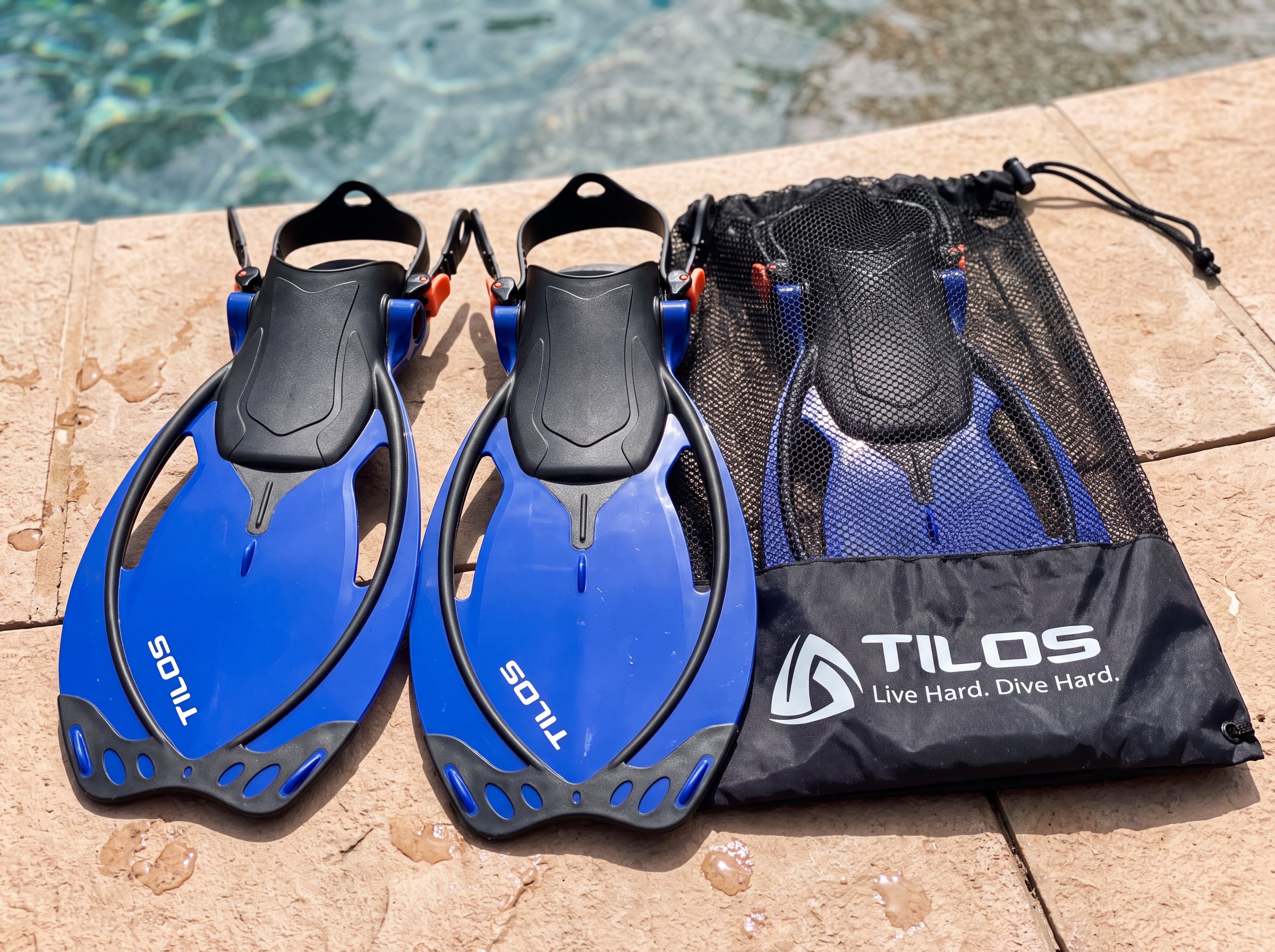Tilos Vulcan Jr kids snorkel fins in blue, poolside with mesh travel bag